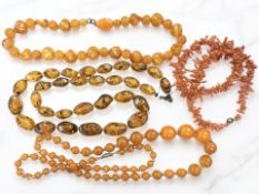 A group of coral and amber-coloured necklaces.
