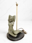 An Art Deco style figural table lamp surmounted by a green composition seated nude female,