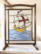 An early 20th century mahogany and stained glass fire screen depicting a sailing ship, height 87 cm.