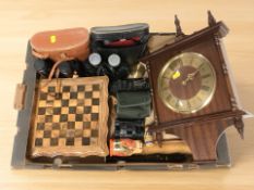 A box of binoculars, wall clock, miniature chess set with board,
