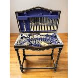 An Edwardian oak serpentine front cutlery canteen on barley twist supports containing a service of