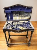 An Edwardian oak serpentine front cutlery canteen on barley twist supports containing a service of