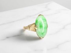 A cabochon jade ring, in chased foliate setting to a plain shank, stamped 585,