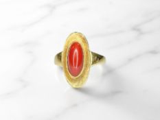 A coral ring, the ovoid cabochon stone within a sunken setting, stamped 750, size O.