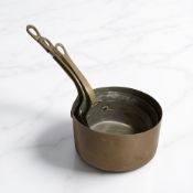 A group of three brass and copper sauce pans