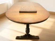 An Ercol stained elm oval extending refectory dining table with leaf,