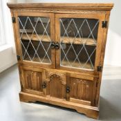 An oak linen fold bookcase with leaded glass doors, width 84 cm.