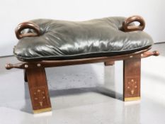 An Eastern hardwood and brass inlaid camel stool with black leather cushion, length 80 cm.