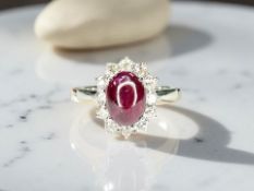 An 18ct white gold cabochon ruby and diamond cluster ring, size M/N.