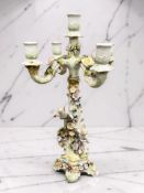 An early 20th century continental encrusted four branch candelabrum surmounted by cherub figures,
