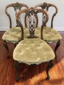 A set of three carved walnut dining chairs on cabriole legs.