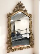 An ornate reproduction gilt over mantel mirror, 94 cm x 142 cm.