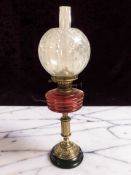A brass Duplex oil lamp with red glass reservoir, height 59 cm.
