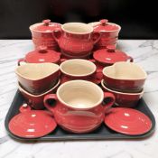 A collection of Le Creuset red glazed ceramic kitchen jars and pots.