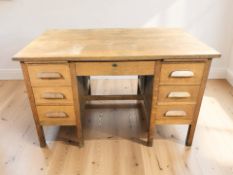 A mid-century oak twin pedestal seven drawer desk, 126 cm x 77 cm x 79 cm.