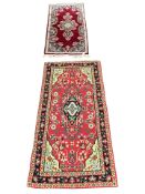 An Iranian rug on red ground, 140 cm x 60 cm, together with a further similar woolen rug.