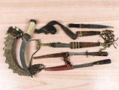 A group of ethnic and tribal weapons including several African knives in leather sheaves,