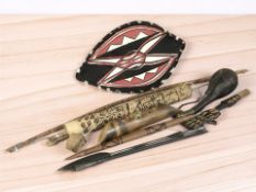 A group of tribal weapons including a bow and arrows, spearheads, leather powder flasks,