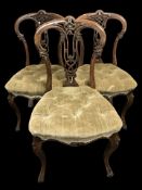 A set of three Victorian carved walnut dining chairs in buttoned upholstery.