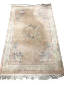 A Chinese woolen rug on pink ground decorated with dragons, 261 cm x 154 cm.