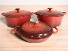 A pair of Le Creuset enameled red enameled cast iron twin handled cooking pots, with lids,