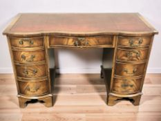 A 20th century mahogany serpentine front nine drawer writing desk with tooled leather inset top,