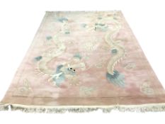 A Chinese woolen carpet on pink ground decorated with dragons, 384 cm x 270 cm.