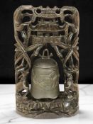 A Chinese patinated bronze gong in heavily carved hardwood surround, circa 1900, height 46 cm.