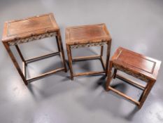 A graduated set of three Chinese carved hardwood nesting tables, largest 50 cm wide.