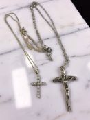 Two silver crucifix pendants on chains.