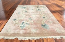 A Chinese woolen carpet on pink ground decorated with dragons, 384 cm x 270 cm.