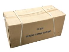A sealing cutter machine, in box, and a roll of shrink wrap.