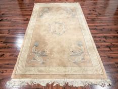 A Chinese woolen rug on pink ground decorated with dragons, 261 cm x 154 cm.