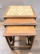 A nest of three teak tile inset tables, width 50 cm.