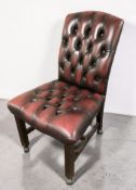 A Chesterfield-style oxblood buttoned leather desk chair on shepherd's castors.