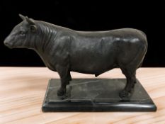 A patinated bronze figure of a bull on black marble plinth, length 26 cm.