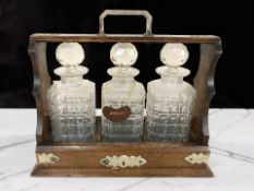 An oak and EPNS three bottle Tantalus, width 36 cm.