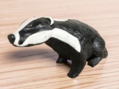 A painted wooden carving of a badger,