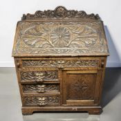 A late Victorian heavily carved oak fall front bureau with 'Green Man' drawer handles,