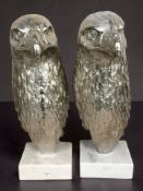 A pair of silvered metal eagle head busts on marble plinths, height 45 cm.