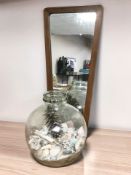 A 1970's teak framed mirror, height 78 cm, and a glass carboy containing assorted sea shells.