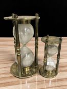 Two brass hour glasses, tallest 24 cm.