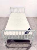 A metal framed 3 ft bed with mattress.