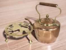 A Victorian copper and brass kettle and a brass trivet.