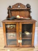 An oak smoker's cabinet containing several pipes.