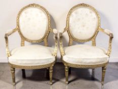 A pair of French gilt wood open salon armchairs in cream satin upholstery, circa 1900, width 67 cm.