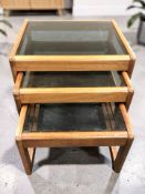 A nest of three teak and smoked glass coffee tables, width 50 cm.