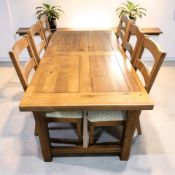 An Oak Furniture Land 6 ft rectangular dining table and a matching set of six ladderback chairs.
