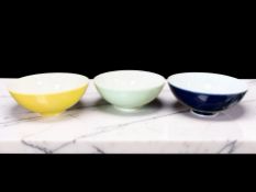 Three Chinese porcelain tea bowls on yellow, green and blue ground,