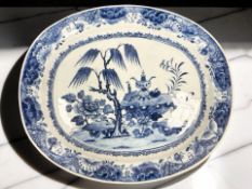 A Chinese blue and white porcelain oval meat plate decorated with a table of scholarly items